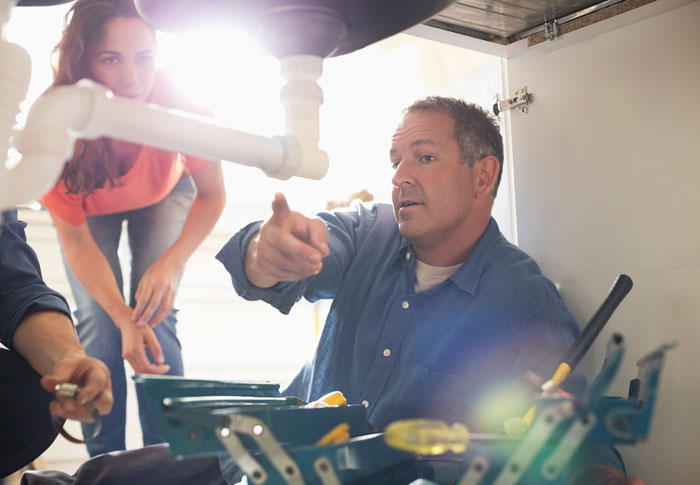 Plumber showing a customer what is wrong under the sink