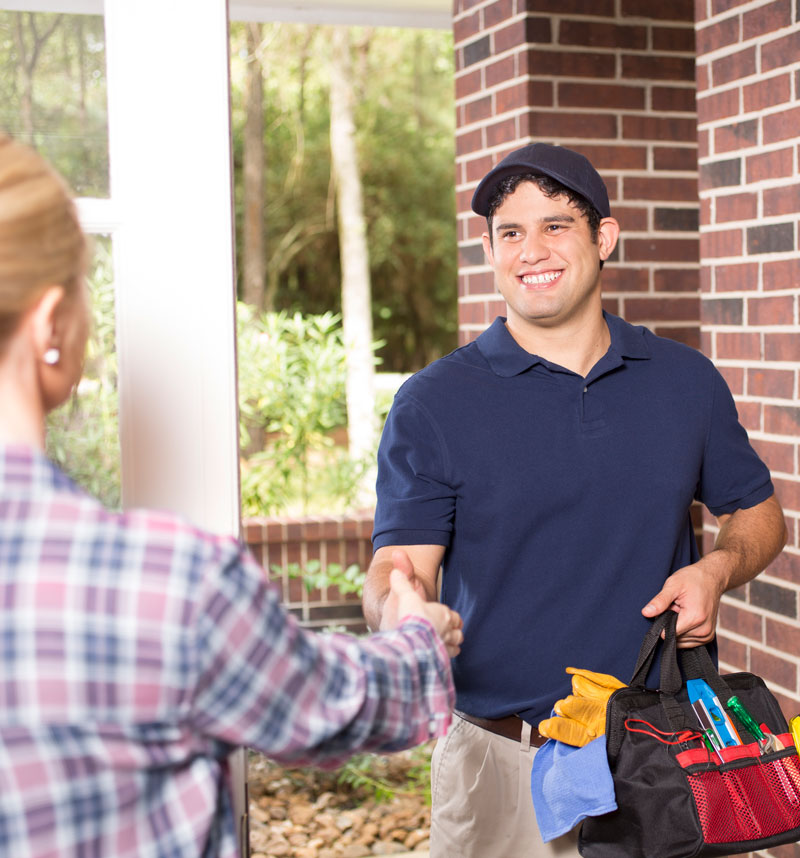 An Electrician smiling as they are greeted at the door by a client