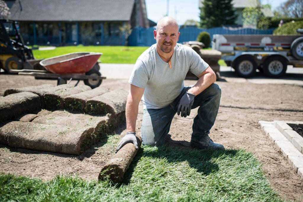 Landscaper laying sod down in a yard and smiling