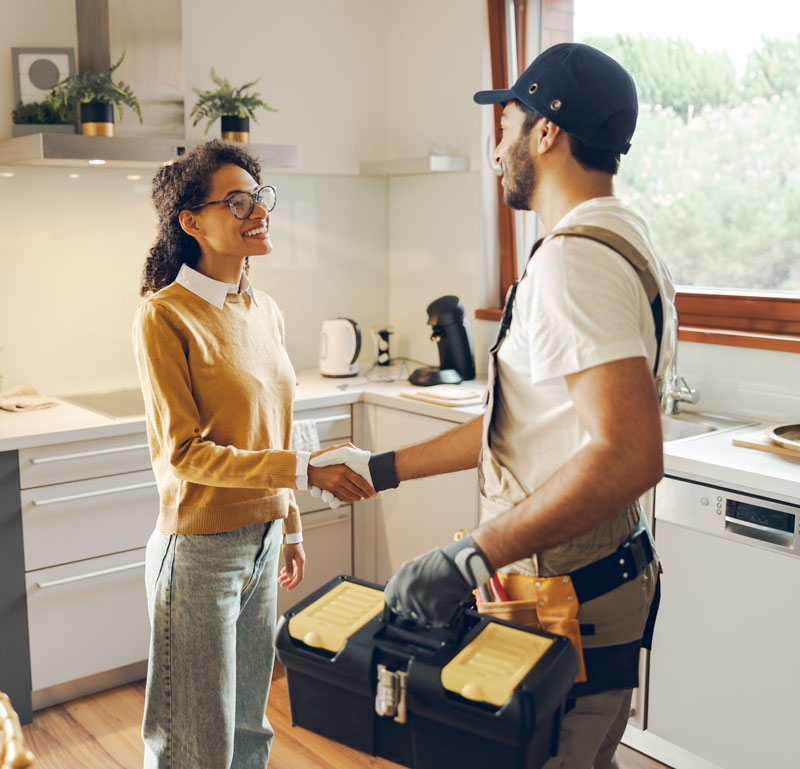 A plumber shaking the hand of a women who requesting his help with a plumbing repair