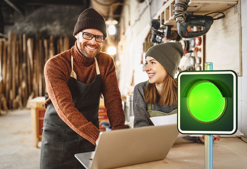 2 business owners smiling and looking at their business profile with an green traffic light overlapping the image