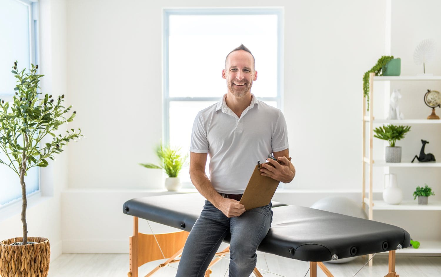 smiling chiropractor sitting on examination table